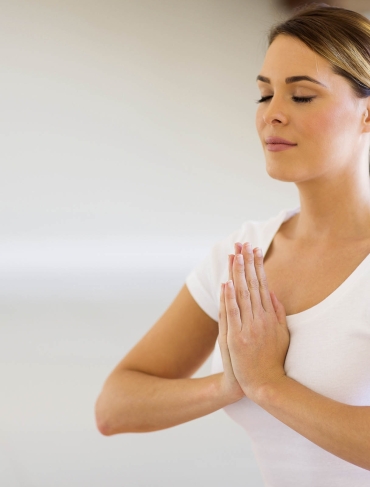 A women meditating with eyes closed and hands folded together