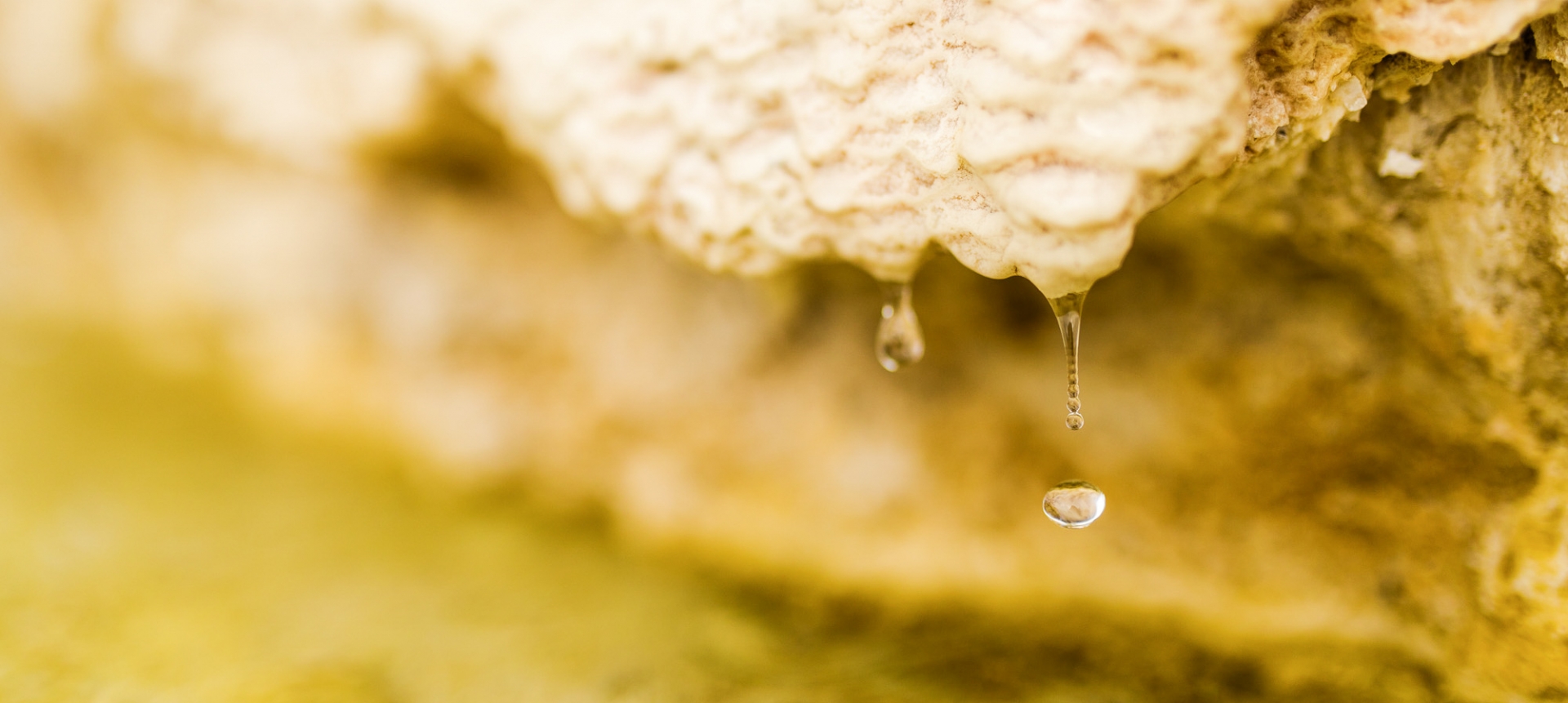 A wide shot of water drops falling from a rock