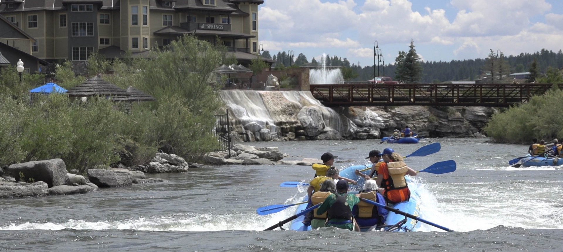 Back shot of group river rafting in San Juan River next to The Springs Resort