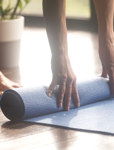 A pair of hand unrolling a yoga mat